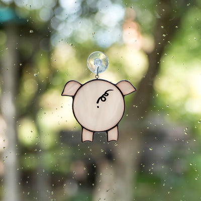 Suncatcher of a stained glass pig looking through the window 