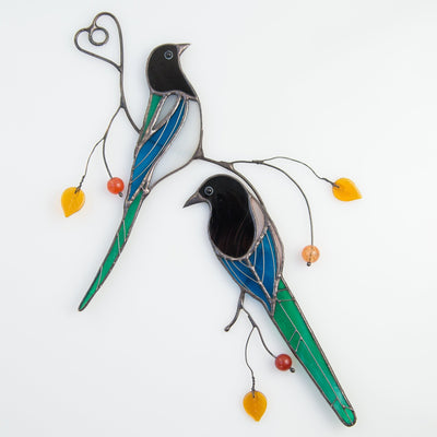A pair of stained glass magpies sitting on the branch window hanging
