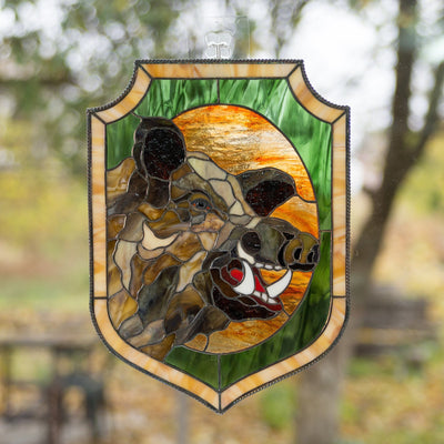 Stained glass panel of a boar with its razors on green and orange background