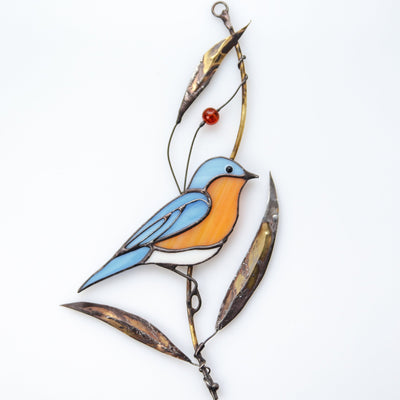 Stained glass bluebird sitting on the branch with bass leaves suncatcher