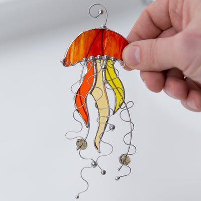Suncatcher of a stained glass orange jellyfish with yellow tentacles 