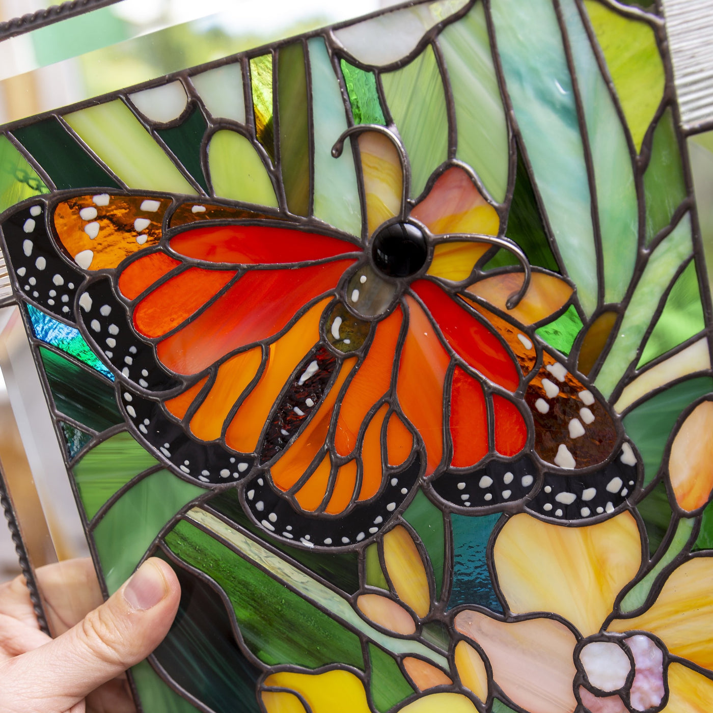 Zoomed stained glass panel depicting monarch butterfly with yellow orchid