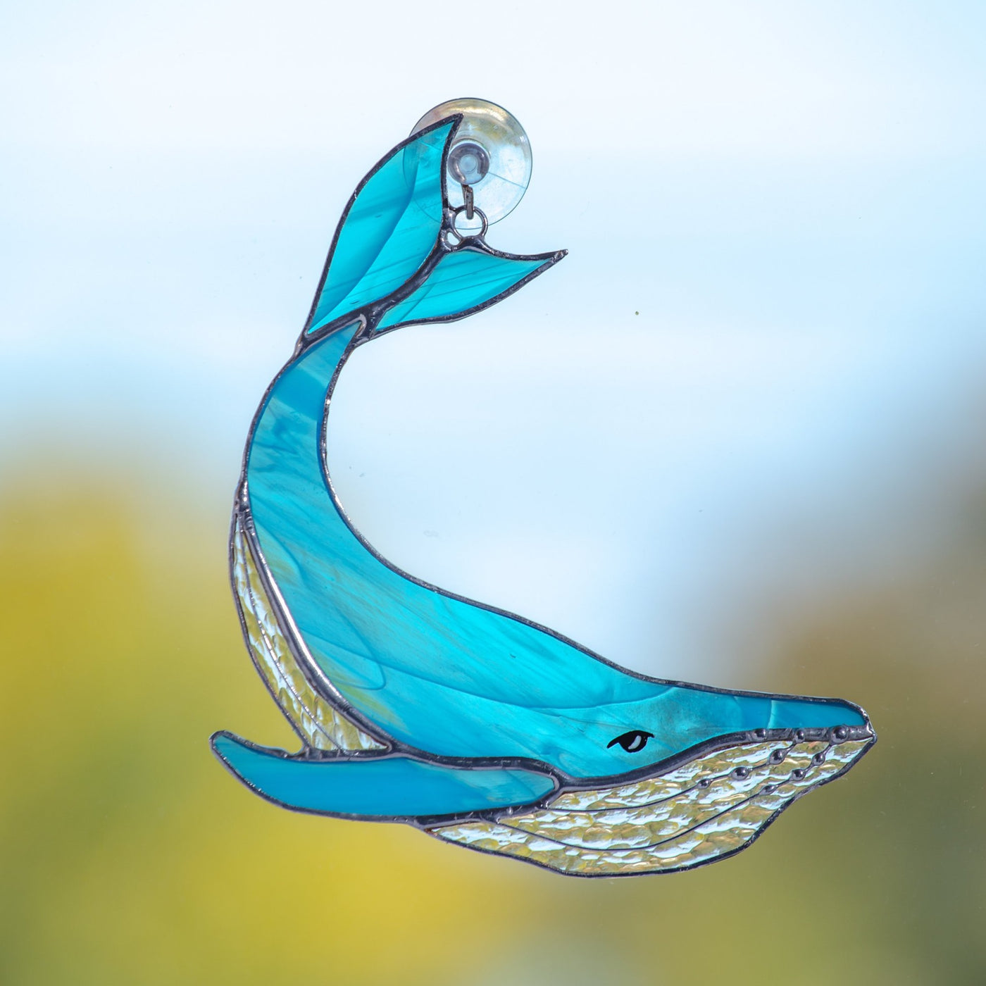 Stained glass whale with tail up of a light blue colour suncatcher for window decoration