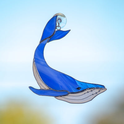Window hanging of a stained glass royal blue whale with tail up
