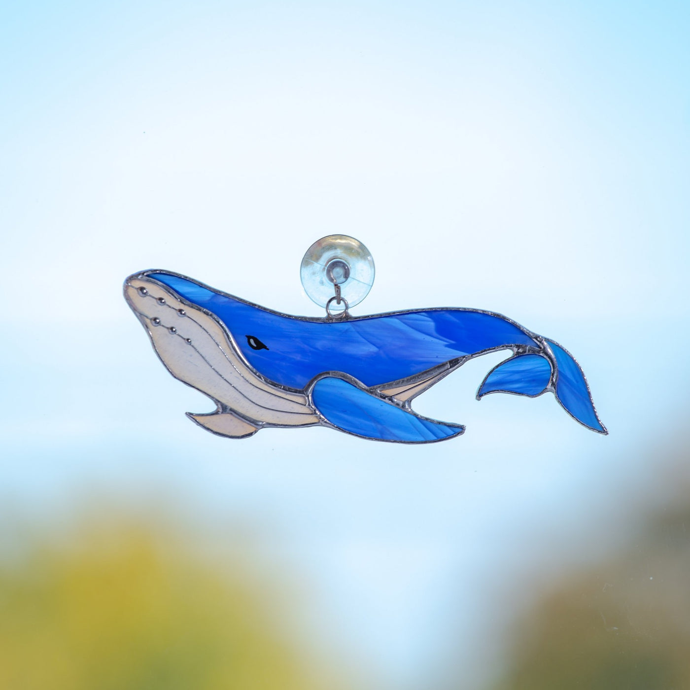 Stained glass royal blue window hanging of a whale with its tail down