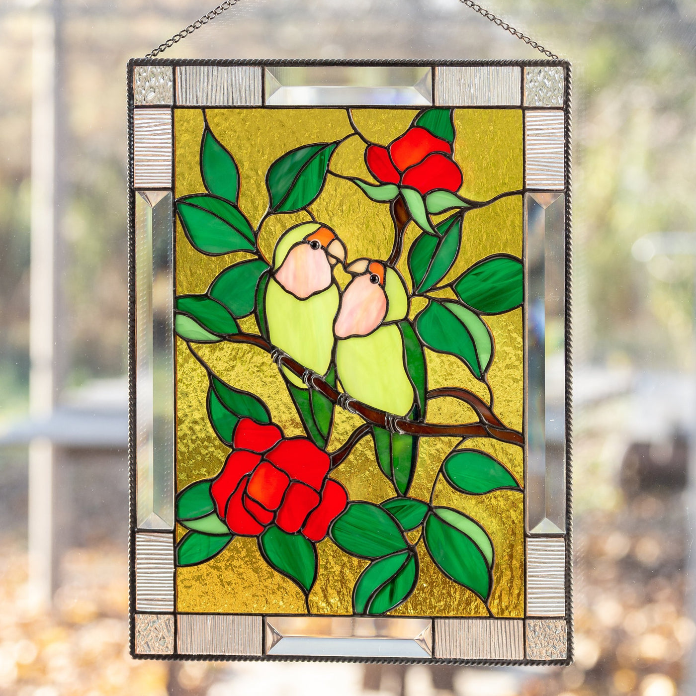 Stained glass panel depicting lovebirds on the branch with red flowers on the yellow background 