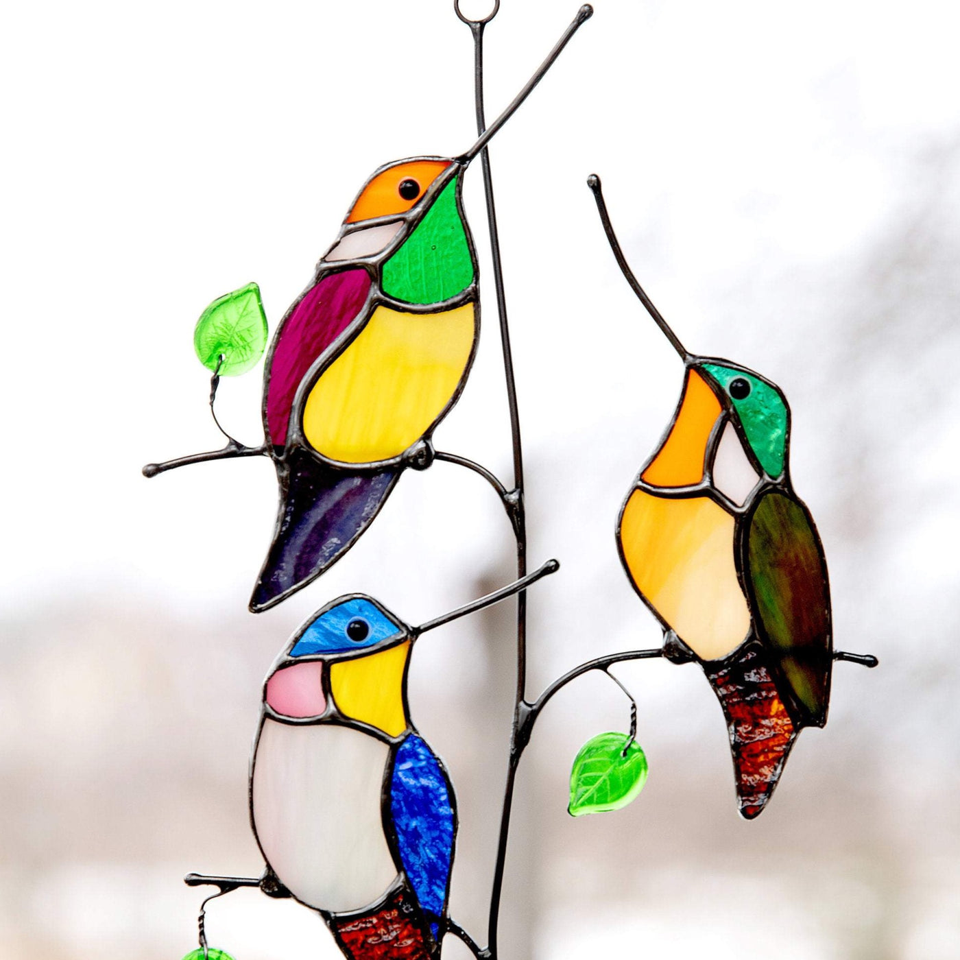 Zoomed stained glass hummingbirds sitting on the vertical branch suncatcher
