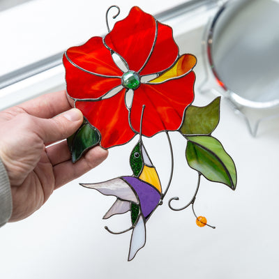 Suncatcher of a stained glass hummingbird with red flower above it