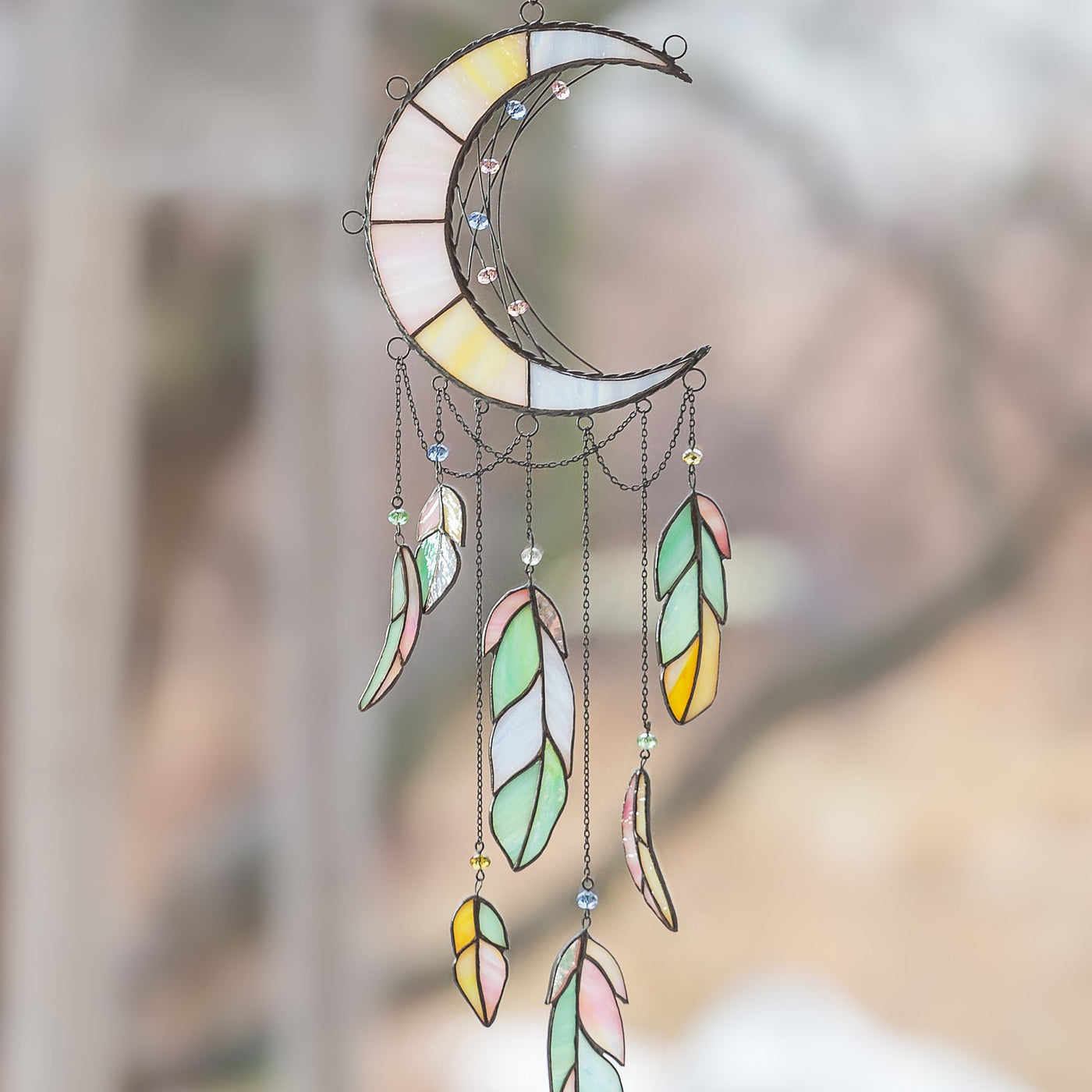 Stained glass moon-shaped dreamcatcher with colourful feathers