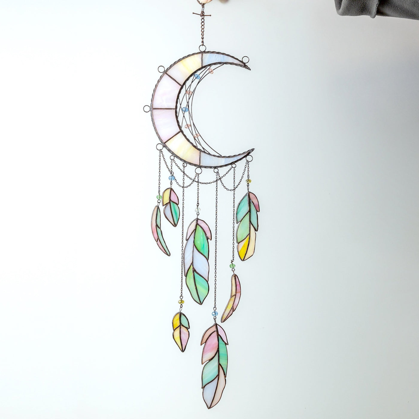 Stained glass moon dreamcatcher with colourful feathers in the lower part 