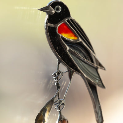 Red-winged zoomed stained glass blackbird sitting on the reeds suncatcher
