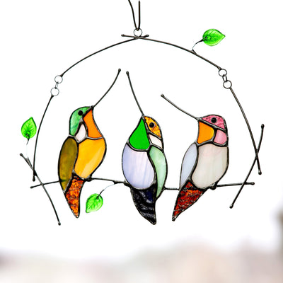 Sitting on the horizontal branch three stained glass hummingbirds suncatcher