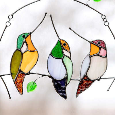 Three zoomed stained glass hummingbirds sitting on the branch window hanging