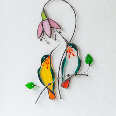 Suncatcher of a stained glass pair of orange and clear glass hummingbirds with pink flower 
