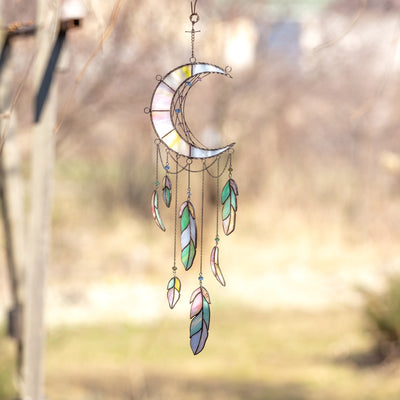 Moon-shaped dreamcatcher of stained glass with feathers below