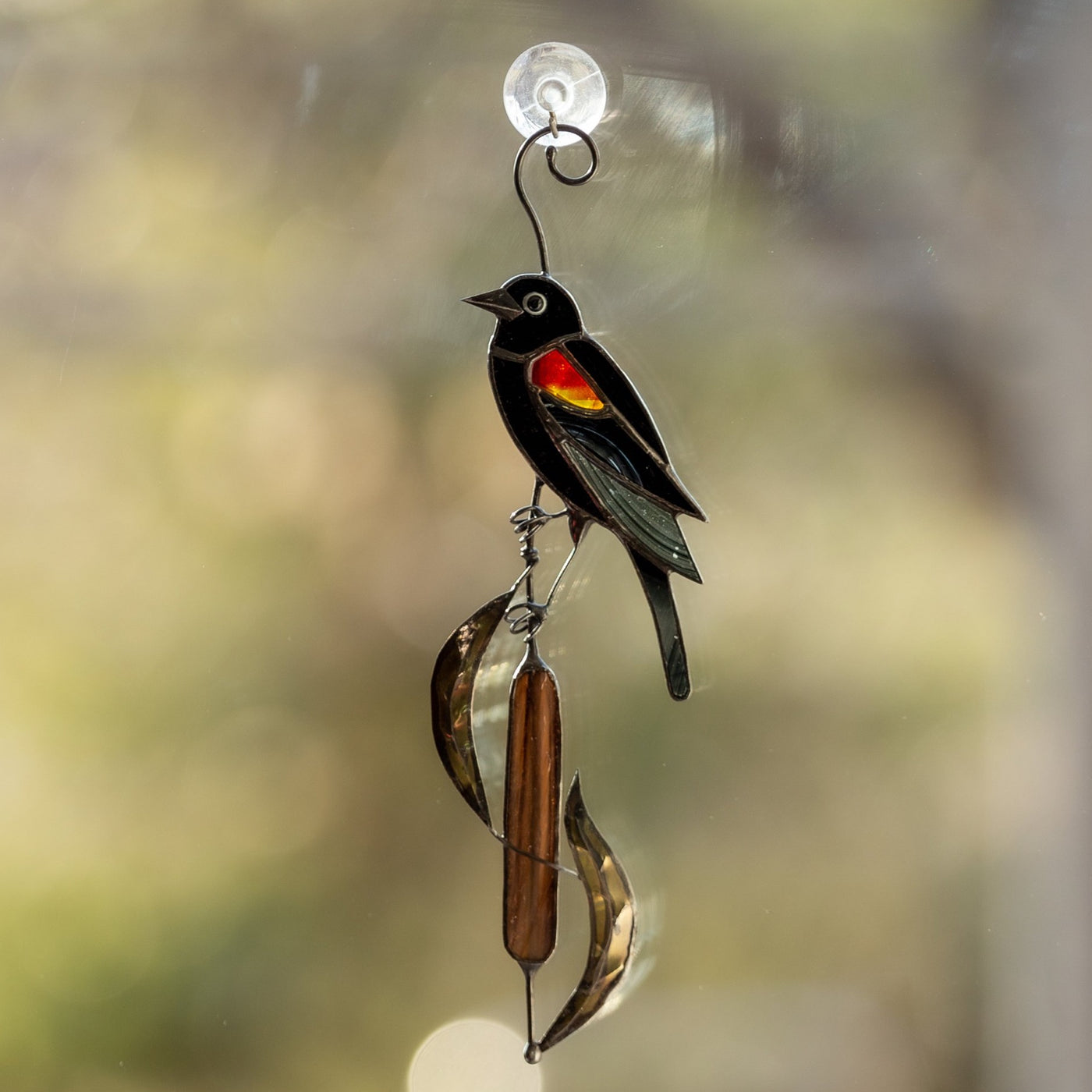 Window hanging of a stained glass red-winged blackbird on the reeds