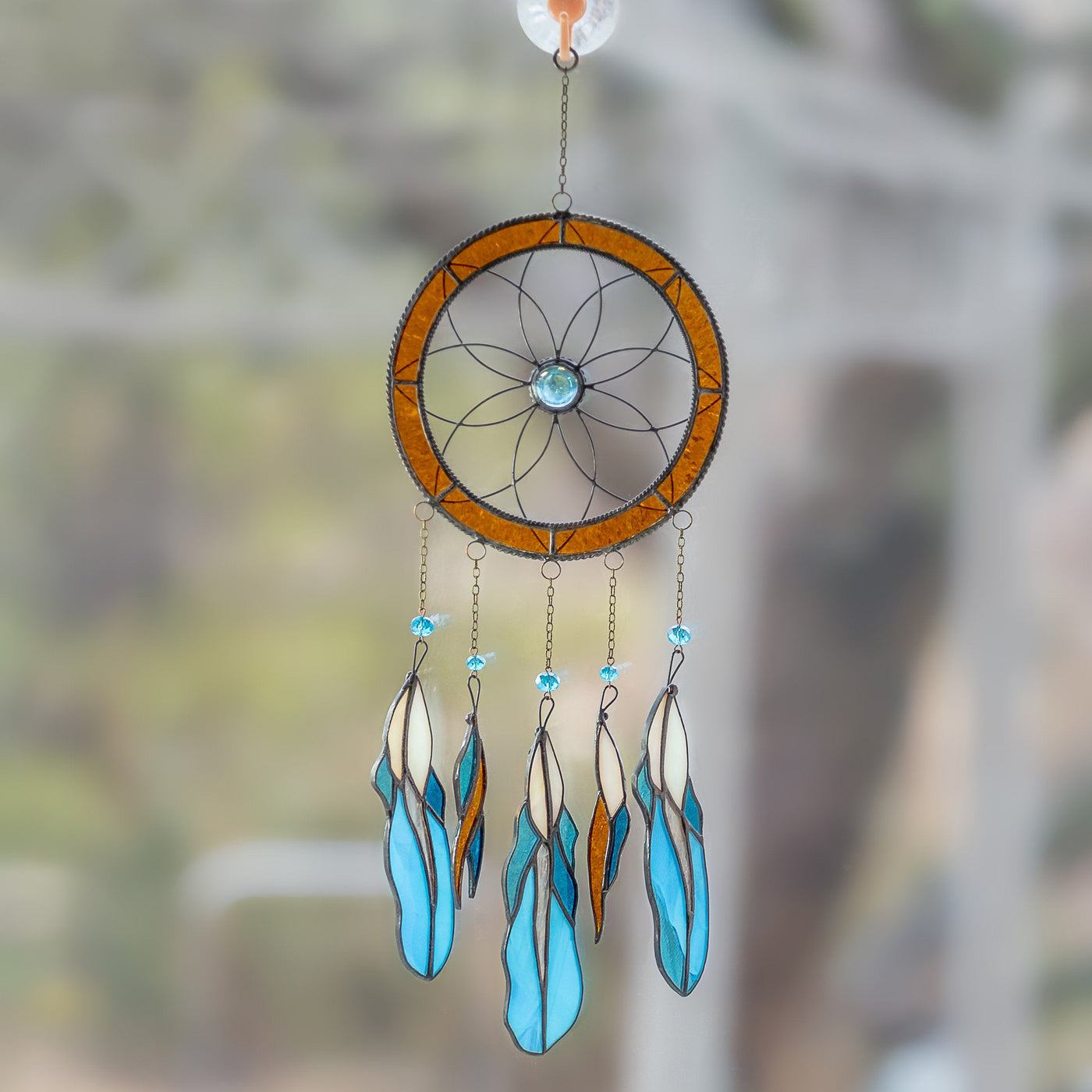 Dreamcatcher of stained glass with blue feathers hanging down