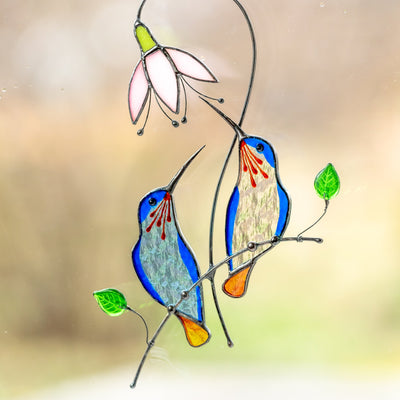 Blue stained glass hummingbirds sitting on the branch with pink flower window hanging